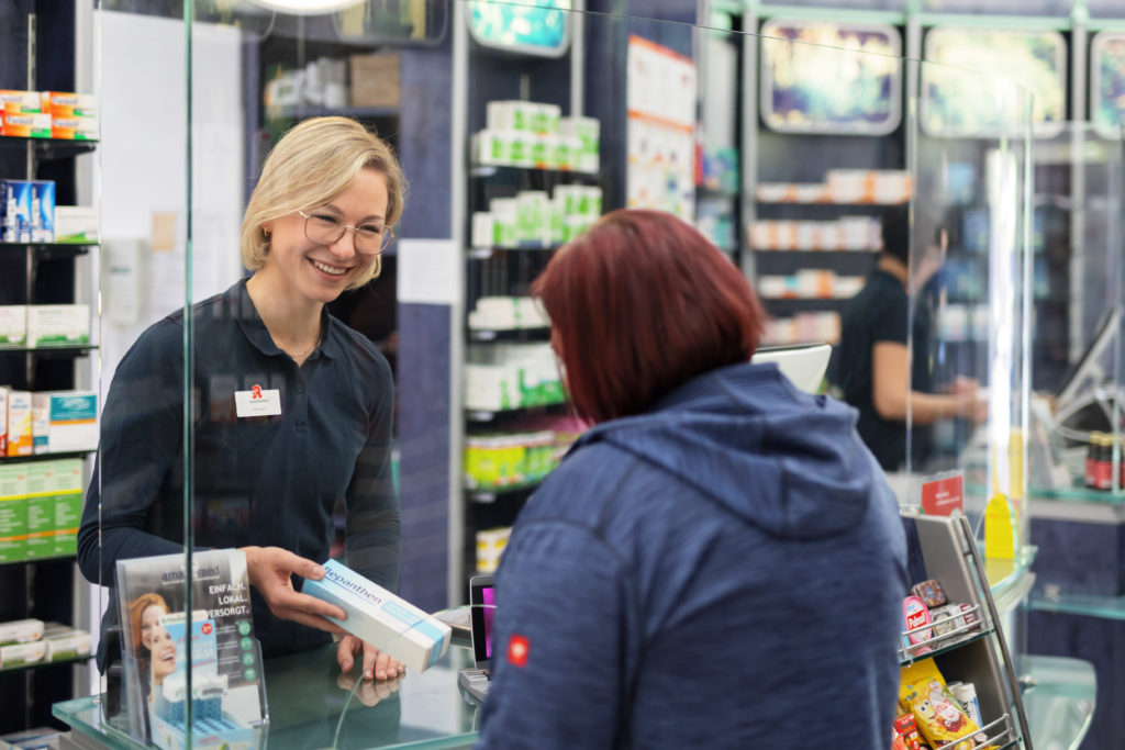Eine Apothekerin überreicht einem Kunden ein Produkt an der Theke in einer Apotheke. In der Trommsdorff Apotheke in Erfurt